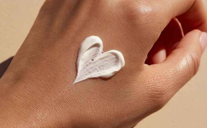imagen de un corazón dibujado con crema corporal sobre una mano femenina